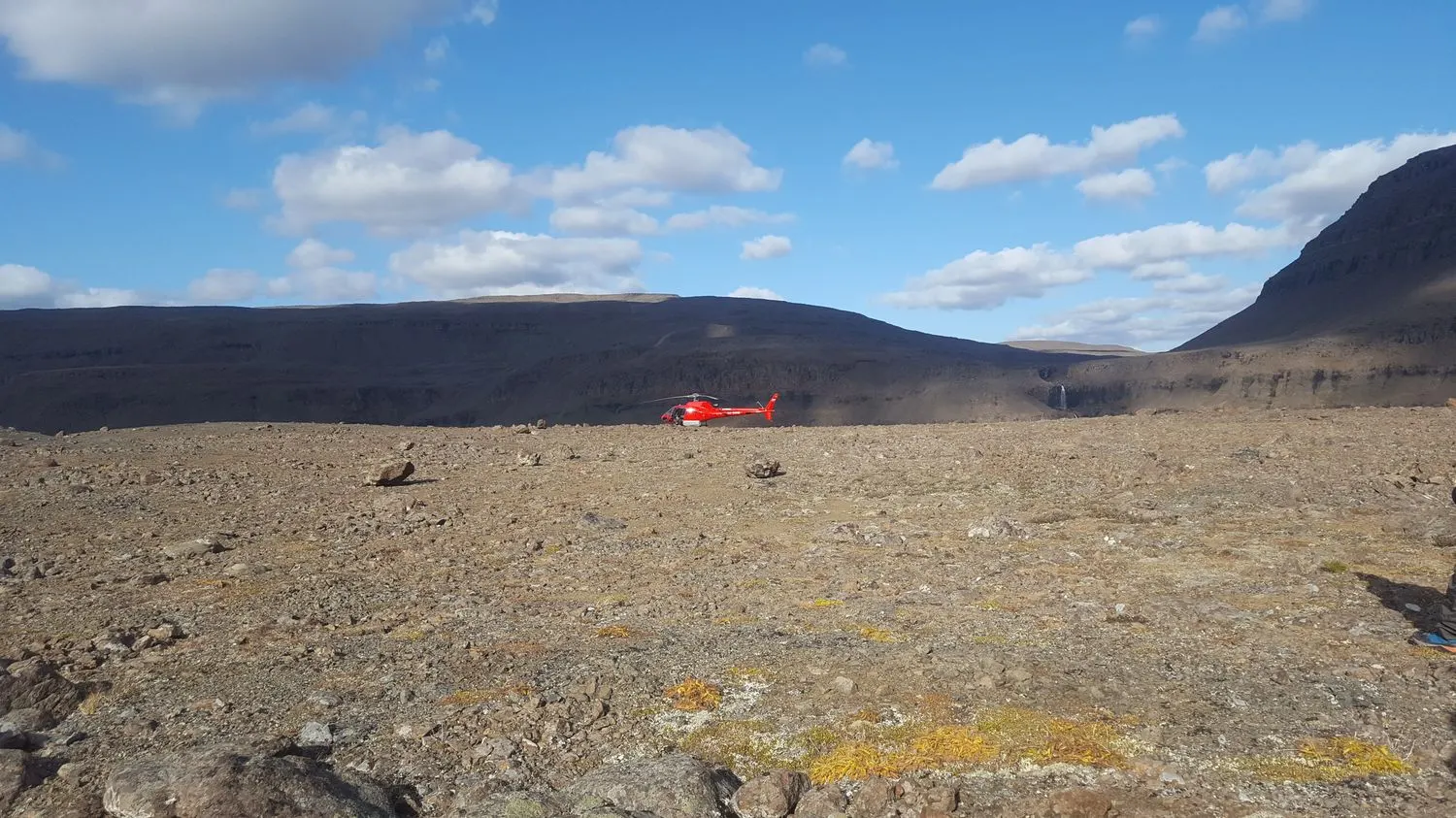 Helicopter landed on the plateau, waterfall in the distance